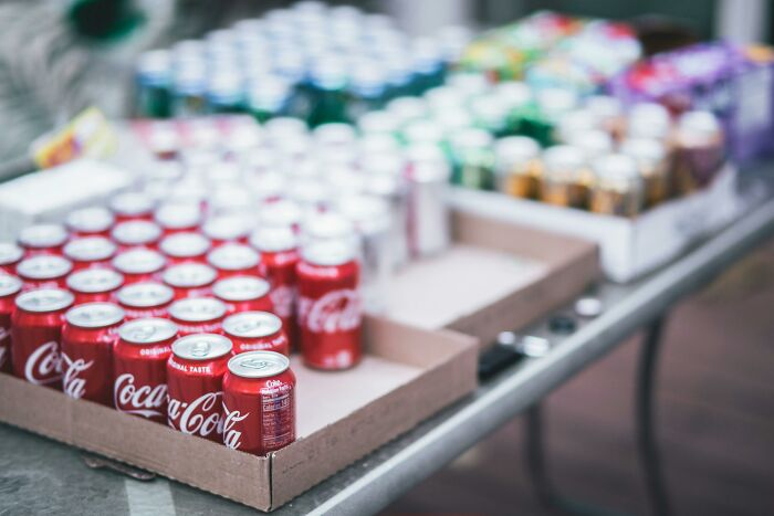 Assorted soda cans on a table, featuring Coca-Cola prominently, showcasing everyday items.