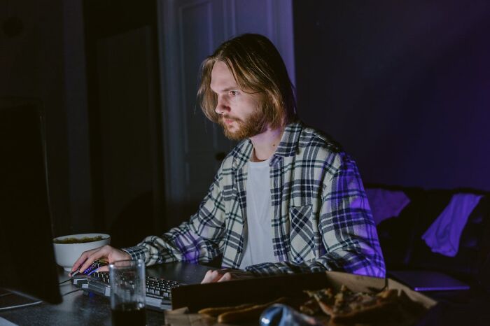 Man in plaid shirt working late at a computer, illustrating the less fun side of a seemingly fun job.