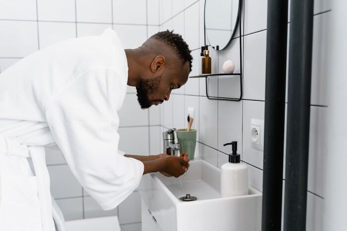 Man practicing good hygiene habits by washing hands at bathroom sink.