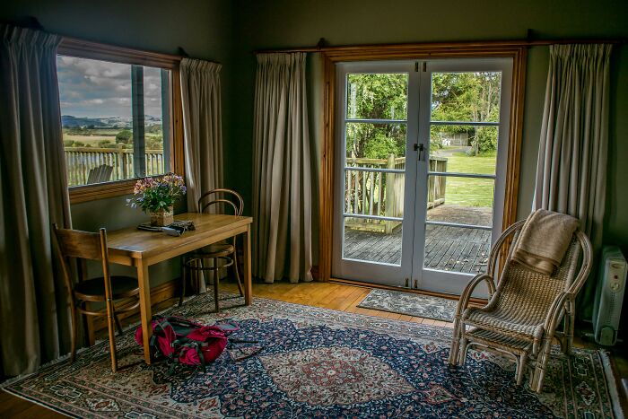 Cozy and frugal home decor with wooden table, wicker chair, and floral rug, exuding a sense of affordable luxury.