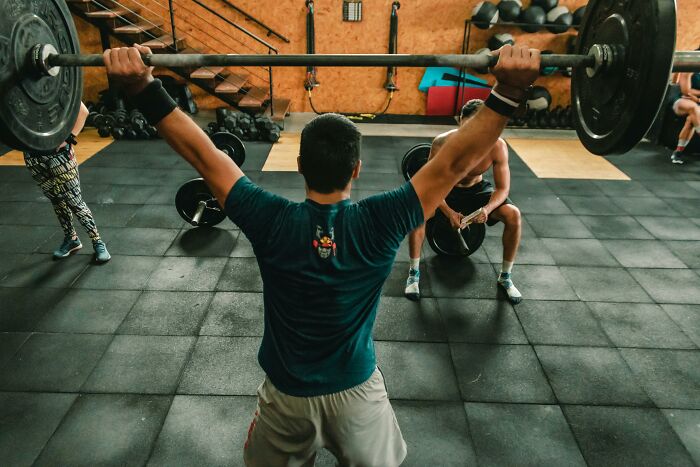 Woman lifting a barbell at the gym, exemplifying the WomenInMaleFields trend.