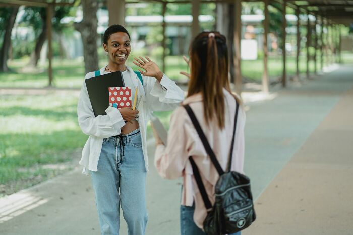 Two people engaging happily outdoors, holding notebooks, discussing judgments.