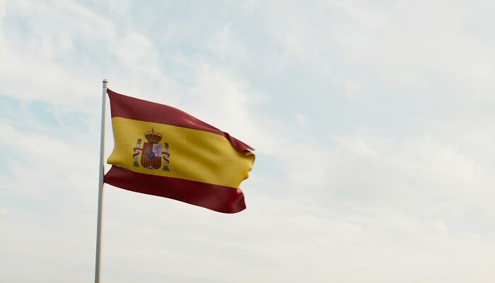 Spanish flag waving against a cloudy sky, related to the realization of dating an idiot.