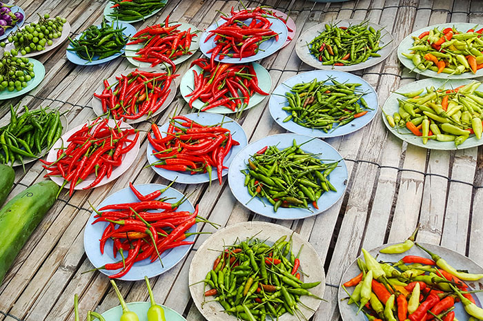 Assorted chili peppers arranged on plates over a bamboo surface, showcasing a vibrant and spicy collection.