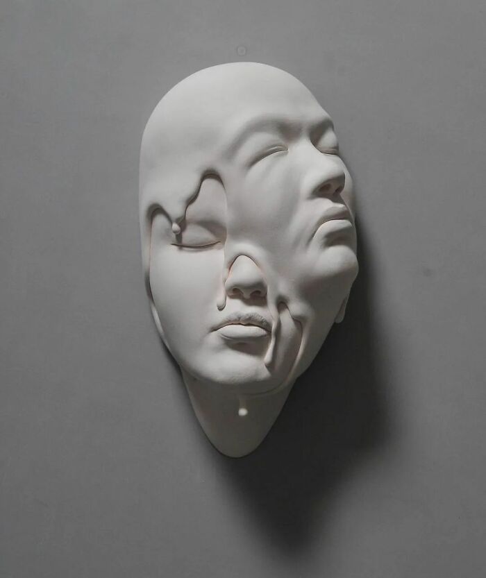 Surrealist sculpture of a melting face blending realism and surrealism with expressive details on a gray background.