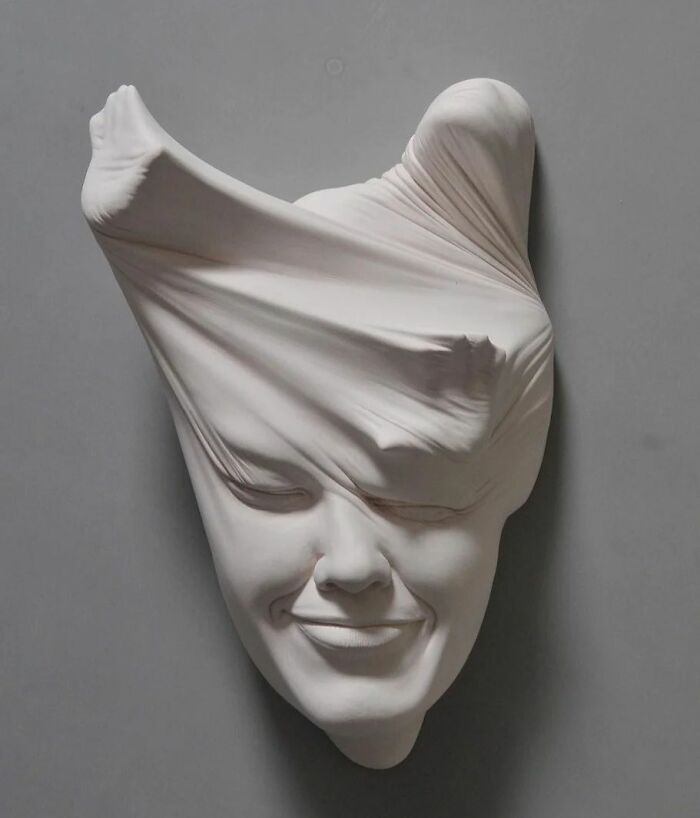 Expressive sculpture blending realism and surrealism in a face with a stretched surface.