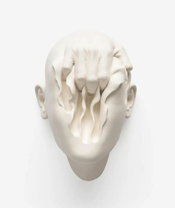 Sculptor's surreal art blending realism, with a distorted human face design in white.