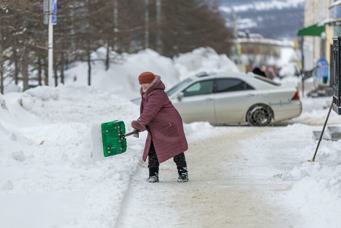 Person shoveling snow near a car on a snowy street, related to netizens sharing moments about marriage decisions.