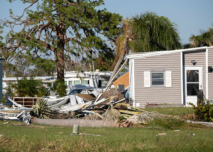 Damaged house and fallen trees, showing the aftermath reality of a storm impact.