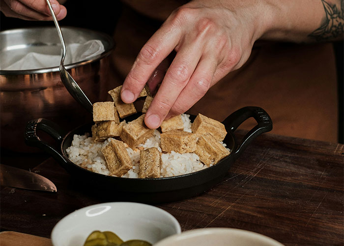 Person preparing food with rice and cubes in a black dish, illustrating the refusal to deliver baby shower food.