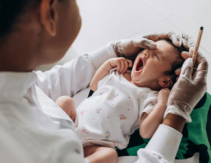 Doctor examines a yawning infant, related to toddler concussion.