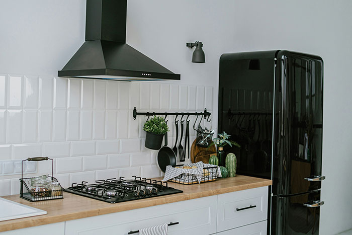 Modern kitchen with black fridge and stove, highlighting an awkward living situation.