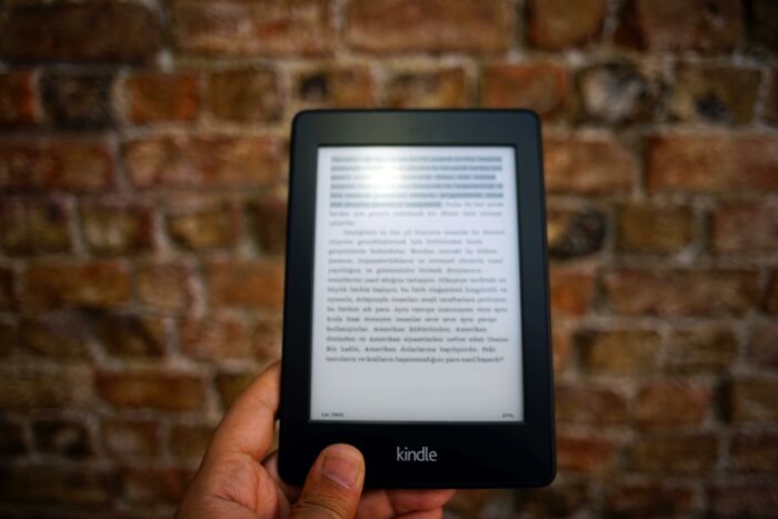 Hand holding a Kindle against a brick wall, symbolizing retirees' best gifts after retirement.