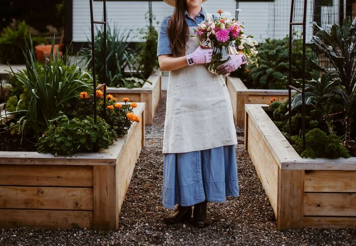 Gardener holding flowers in a raised bed garden, symbolizing a retiree's rewarding gift to themselves.