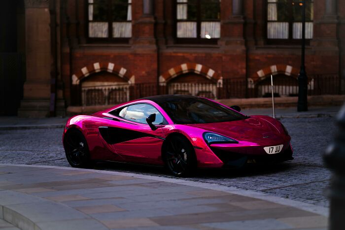 A sleek pink sports car parked on a cobblestone street, reflecting the joy of retirees' best gifts to themselves.