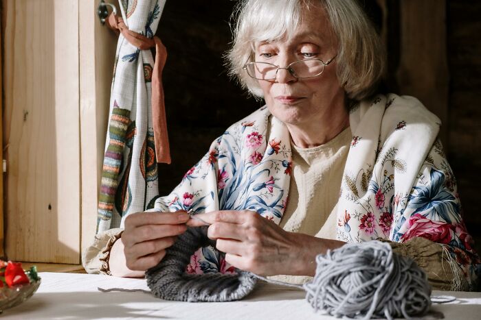 A retiree knitting in a cozy room, surrounded by yarn, enjoying a relaxing hobby after retirement.