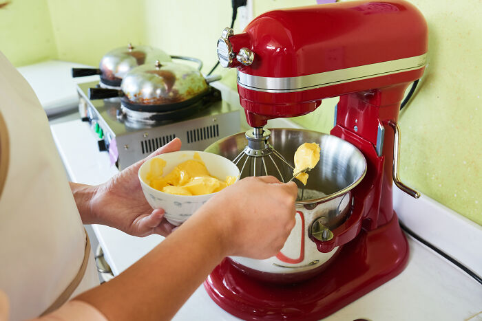 Retiree using a red stand mixer to make butter in a kitchen, showcasing a self-gifted appliance.