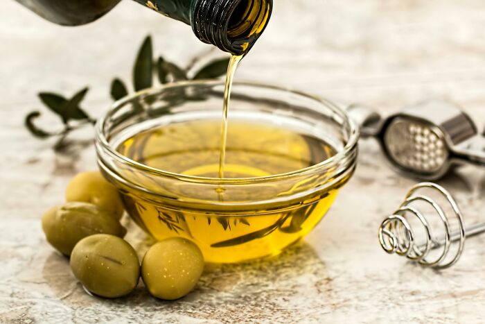 Olive oil being poured into a bowl with olives, symbolizing luxury gifts for retirees.