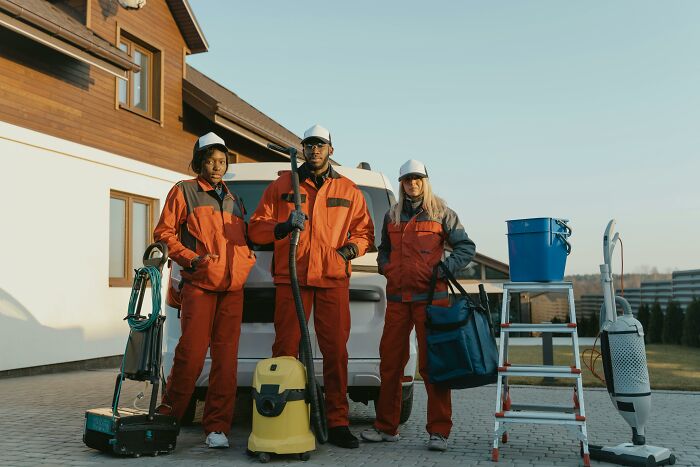 Retirees with cleaning equipment standing in front of a house, showcasing post-retirement gifts to themselves.