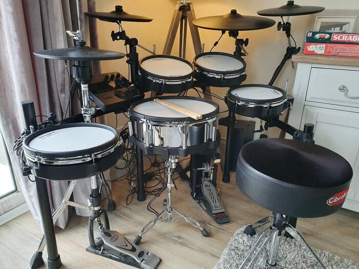 Electronic drum set purchased by a retiree as a personal gift after retirement, set up near a window.