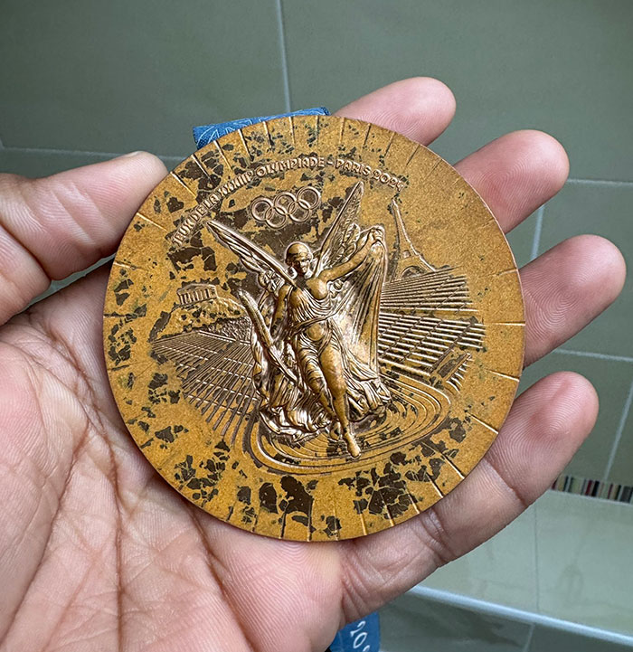 Rusted bronze medal design for French Paris 2024 Olympians, featuring intricate details and iconic symbols.