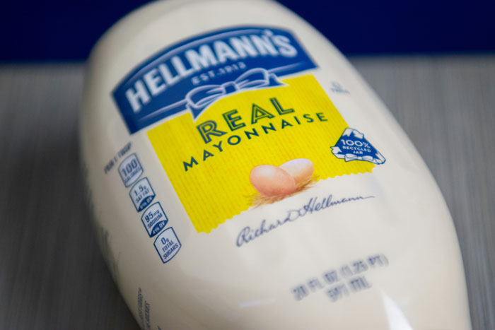 Close-up of a Hellmann's Real Mayonnaise bottle on a table, focusing on the brand and product label.