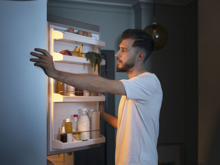 Man checks fridge, concerned about mayonnaise consistency.