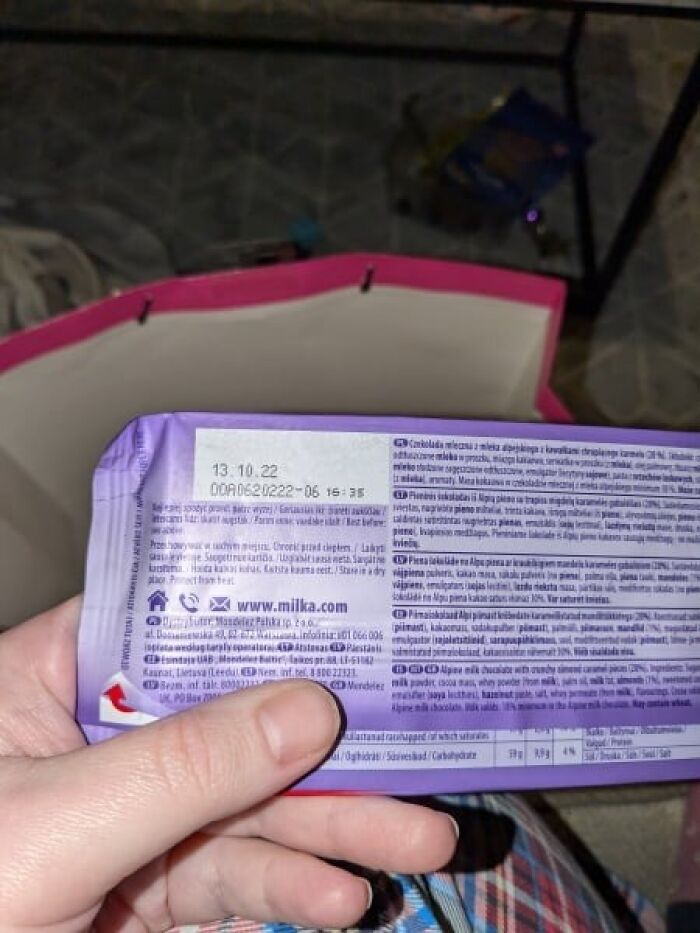 Expired chocolate bar held by a hand, showing past expiration date, possibly a Secret Santa gift.