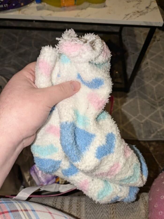 Hand holding a fluffy, multi-colored sock, related to Secret Santa gift expired theme.