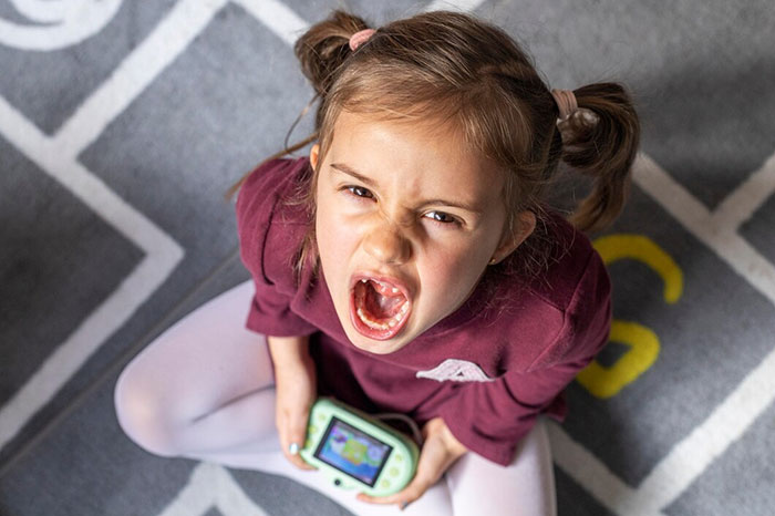 Angry child with a gaming device, illustrating potential signs of terrible parents.