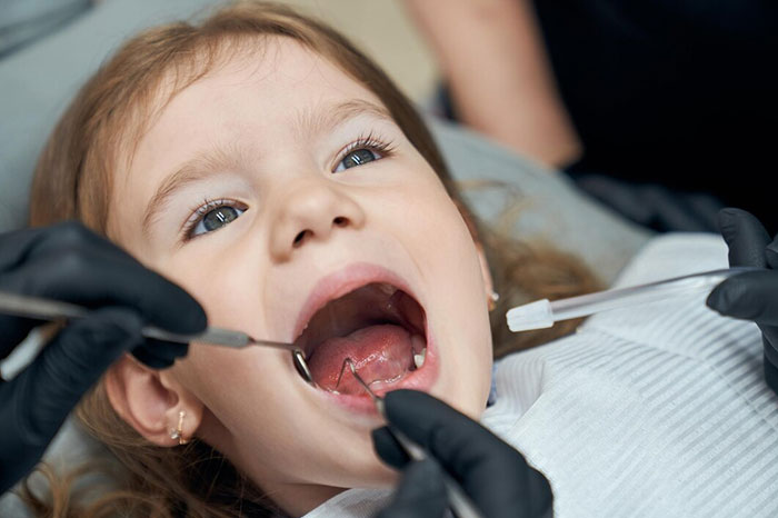 Child at dentist, receiving checkup with dental tools, highlighting signs of terrible parents.