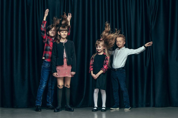 Children posing in front of a black curtain, with playful hairstyles and expressions.