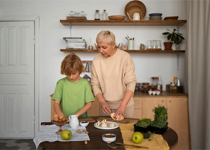 Adult guiding child in kitchen, preparing food together.