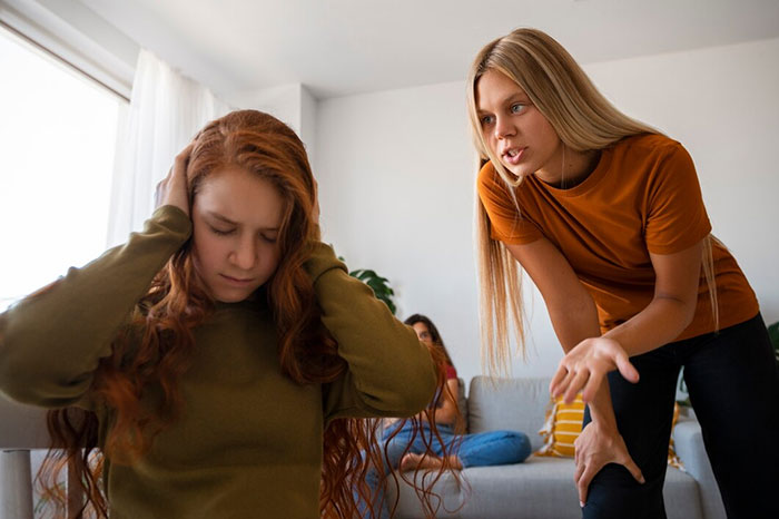 Teen covering ears while adult scolds, illustrating signs of terrible parents.