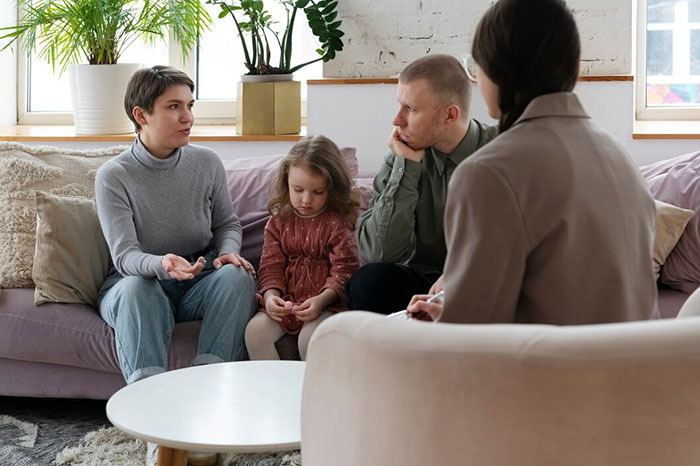 Family conversation on a couch, with adults and a child, illustrating signs of terrible parents.