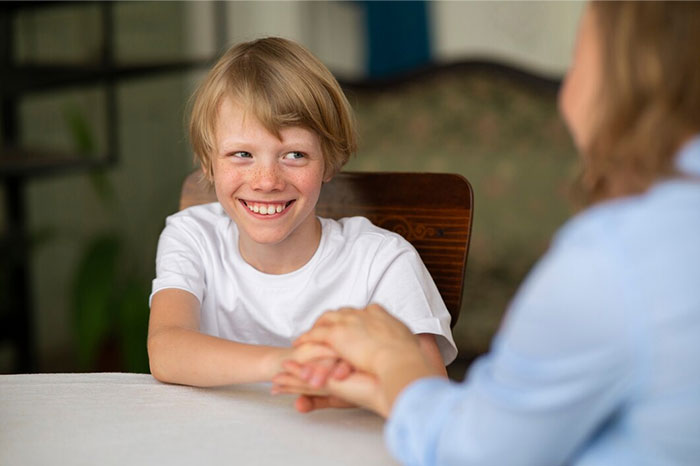 Child smiling while holding hands with an adult, displaying positive interaction contrary to signs of terrible parents.