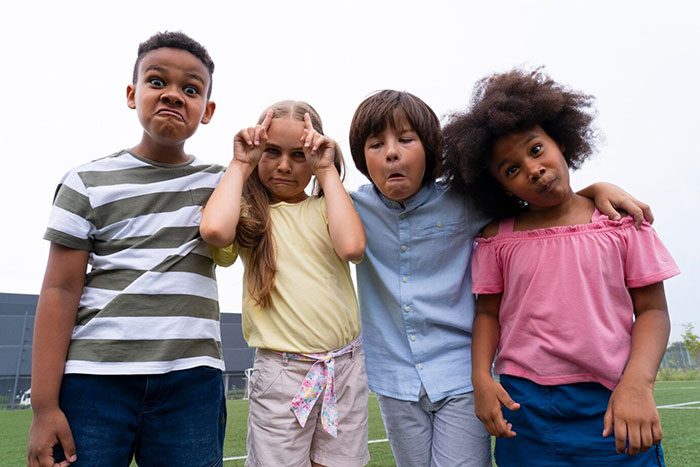 Children making funny faces outdoors, linked to signs of terrible parents.