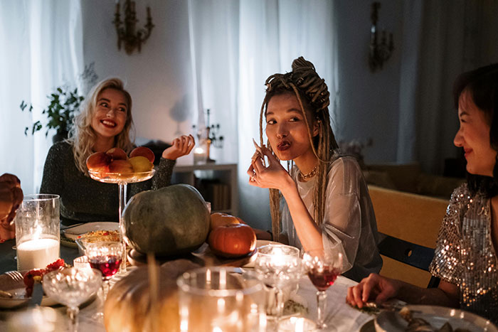 Siblings at a festive dinner table, enjoying a meal together with holiday decorations and candles.