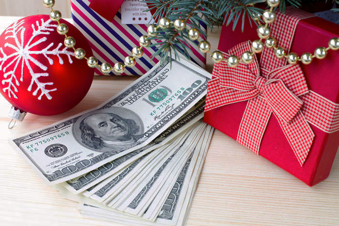 Dollar bills beside festive decorations and a gift box, symbolizing clearing debt during holiday season.