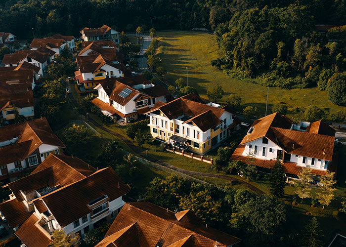 Aerial view of suburban homes showing peaceful neighborhood near lush greenery, balancing homeowner and HOA dynamics.