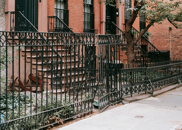 Iron fence and brick townhouse in an urban neighborhood, highlighting a homeowner's response to HOA rules.