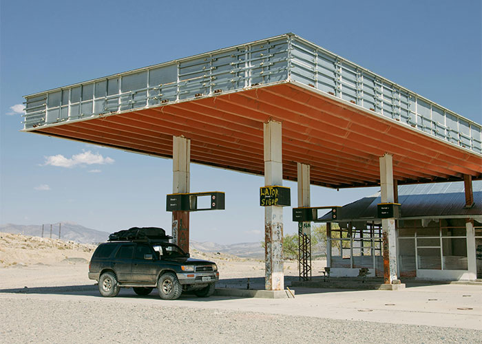 Deserted gas station with SUV parked under canopy, illustrating homeowner rebellion against HOA.