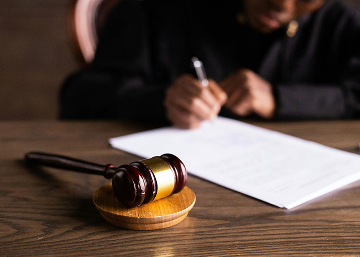 Judge writing at desk with a gavel in focus, symbolizing conflict with HOA.