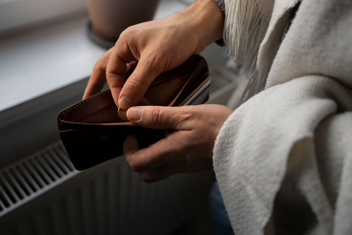 Person holding wallet, considering 50/50 bill split, financial imbalance concept.