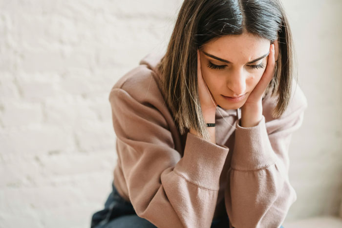 Woman in a sweater looking thoughtful, illustrating the 50/50 bill split debate.