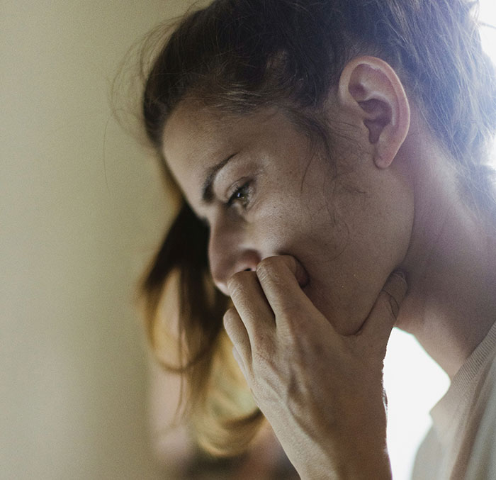 Woman looking concerned, deep in thought about possible fraud involving family debt.