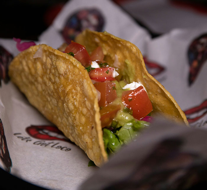 Crispy taco with fresh toppings on branded paper, highlighting cultural curiosity in Canadian dining.