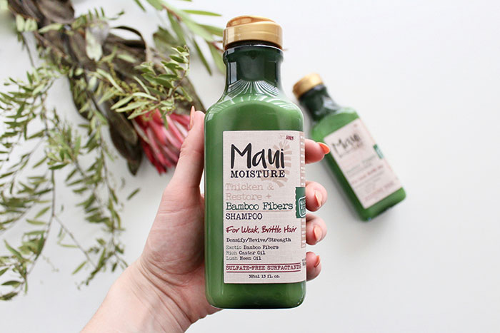 Green Maui Moisture shampoo bottle held in hand; bamboo fibers for weak, brittle hair.