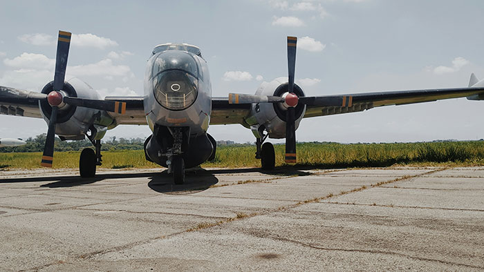 Vintage Canadian plane parked on a sunny airfield, propellers visible against a clear sky.