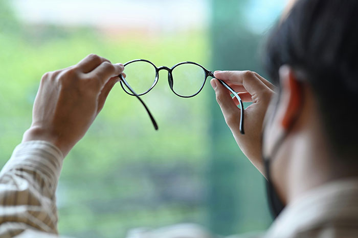 Person holding glasses, contemplating a question about speaking Canadian.